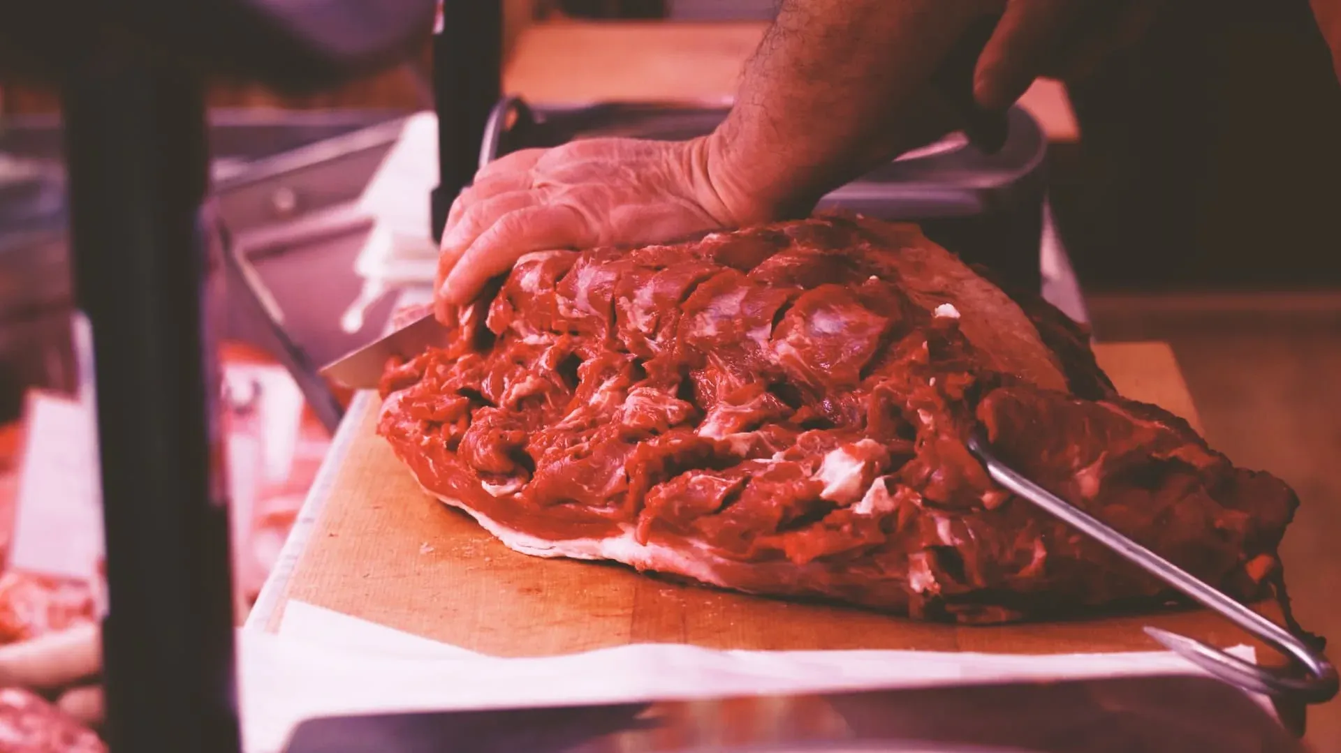 Un taglio di carne sul tagliere, le mani del macellaio