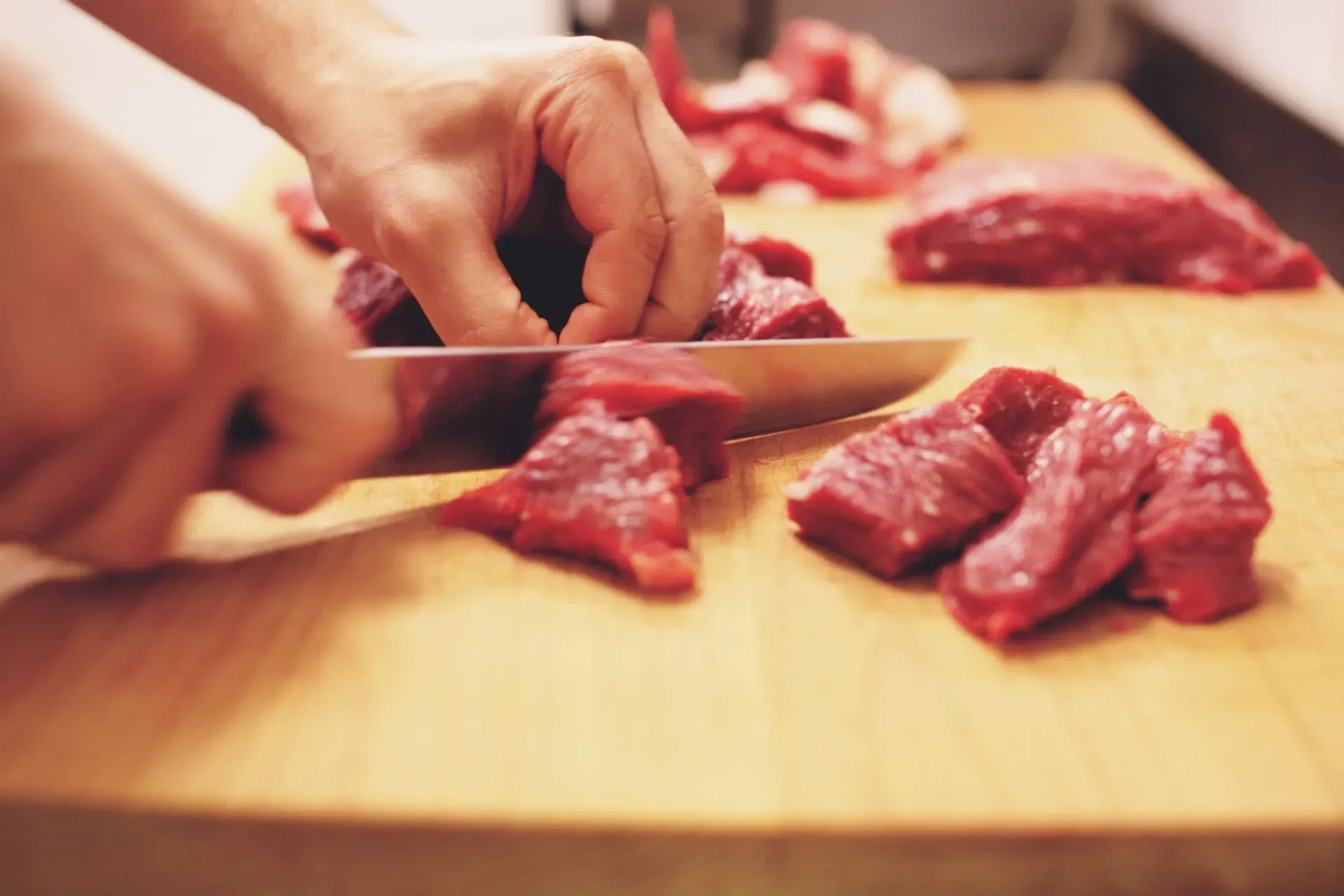 Mani che tagliano la carne sul tagliere